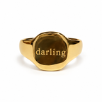 Single gold Darling signet ring on white background