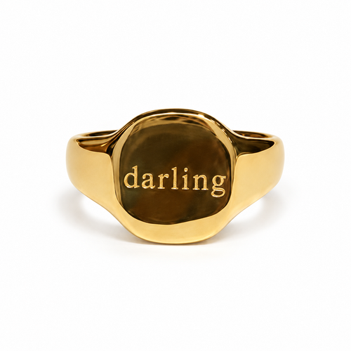 Single gold Darling signet ring on white background